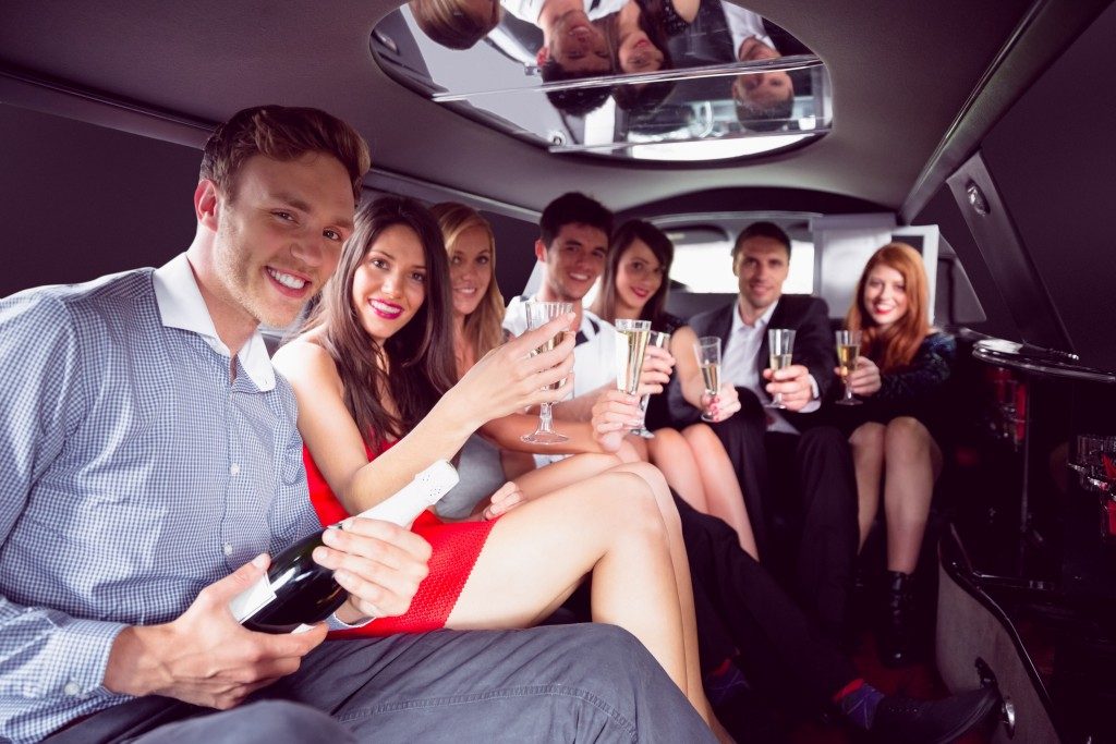 Happy friends drinking champagne in limousine on a night ou