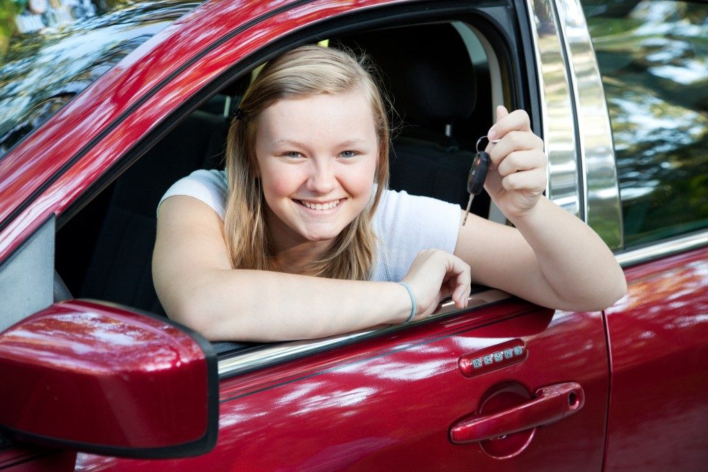 blond teenage girl sitting in her new car
