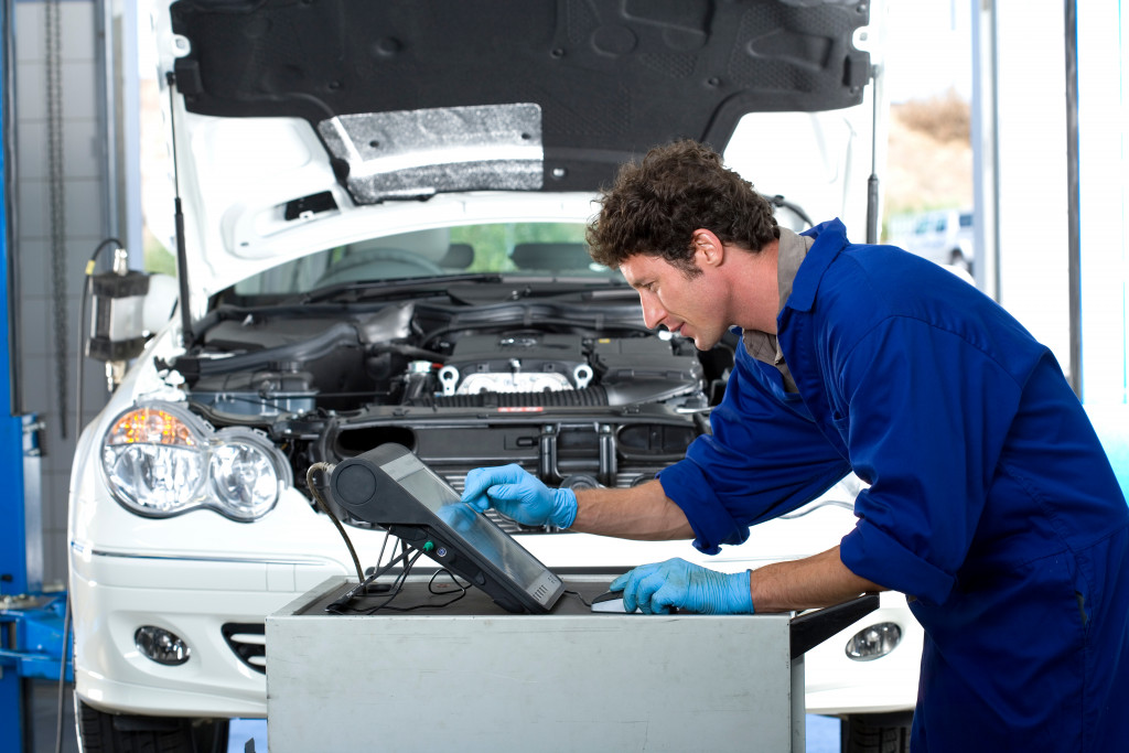 A car mechanic using technology to diagnose car problem